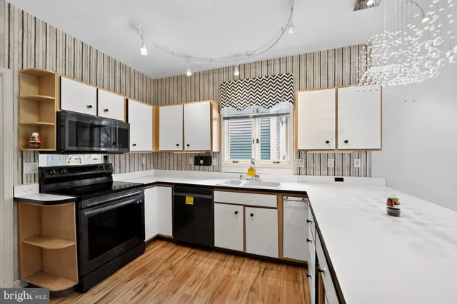 a kitchen with stainless steel appliances a sink cabinets and wooden floor