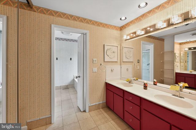 a spacious bathroom with a double vanity sink a large mirror and a shower