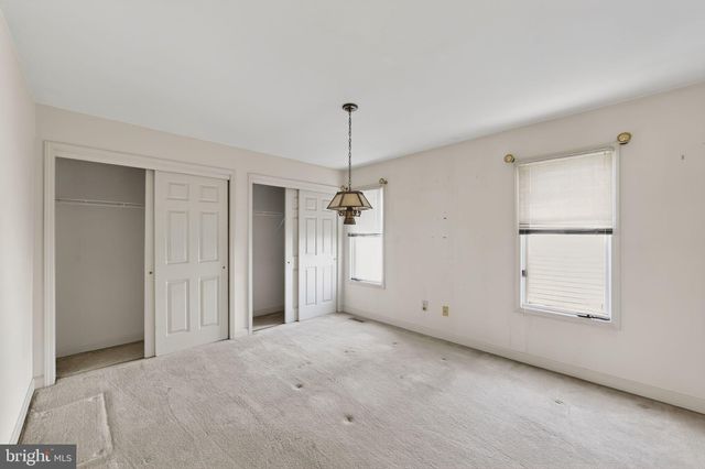 an empty room with chandelier fan and windows