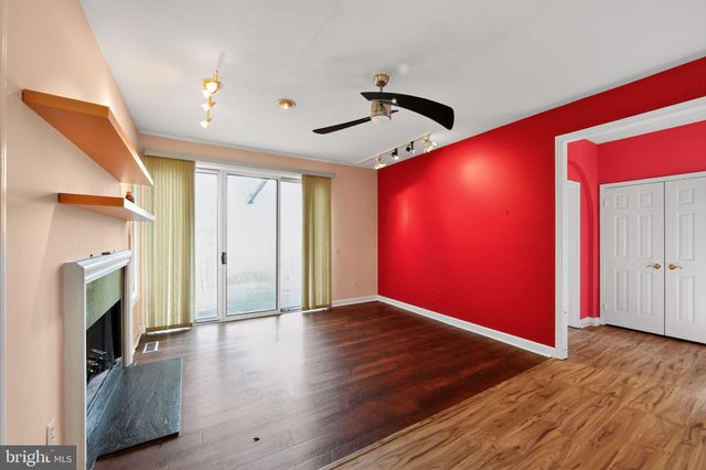 a view of an empty room with wooden floor and a fireplace