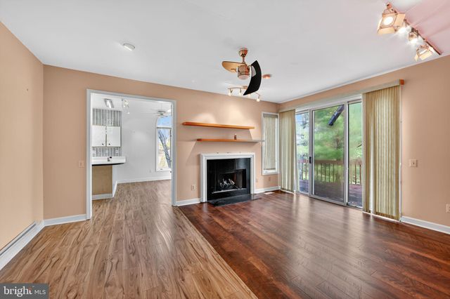 a view of an empty room with wooden floor fireplace and a window