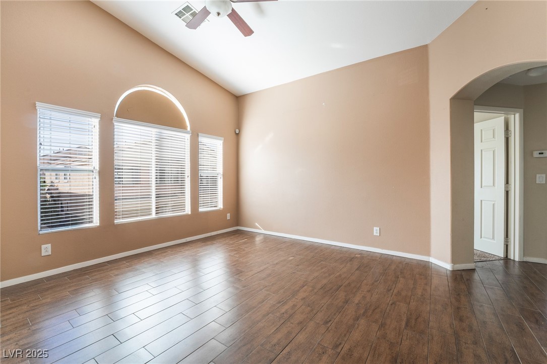 1570 Rusty Ridge Lane Henderson, NV 89002 - Photo 11 of 35 Empty room with arched walkways, plenty of natural light, dark wood finished floors, and ceiling fan