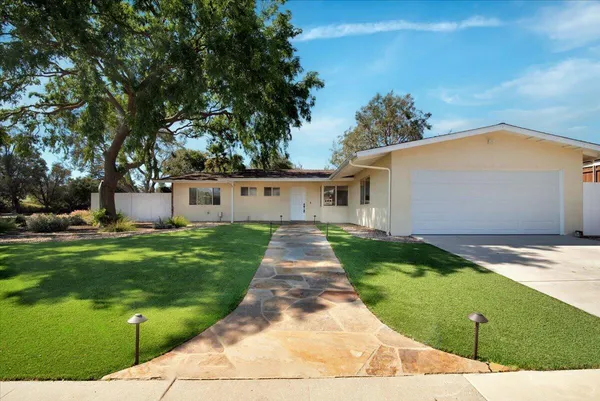 a front view of a house with a yard and potted plants
