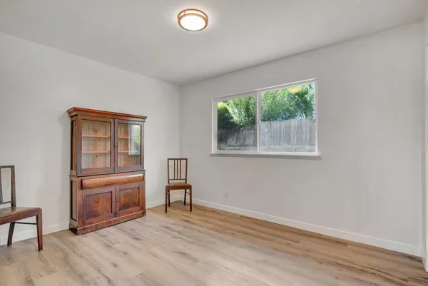 a view of an empty room with a window and wooden floor
