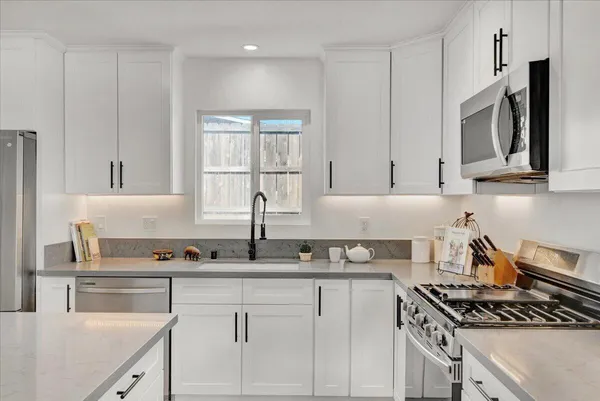 a kitchen with granite countertop white cabinets stainless steel appliances and a sink
