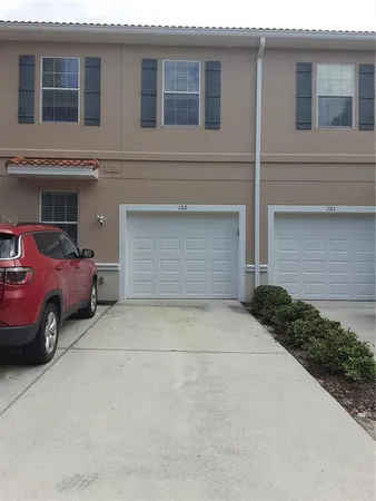 a front view of a house with lots of flowers and trees