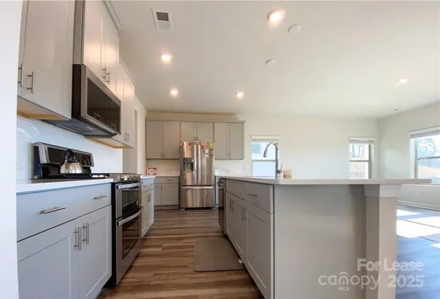 a kitchen with stainless steel appliances granite countertop a sink and dishwasher a stove top oven with wooden floor