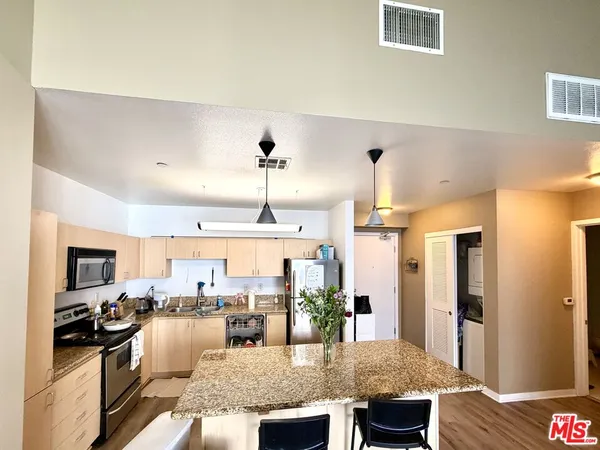 a kitchen with stainless steel appliances granite countertop sink stove refrigerator and cabinets