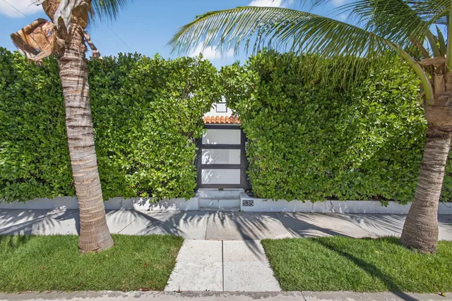 a front view of a house with a yard and potted plants