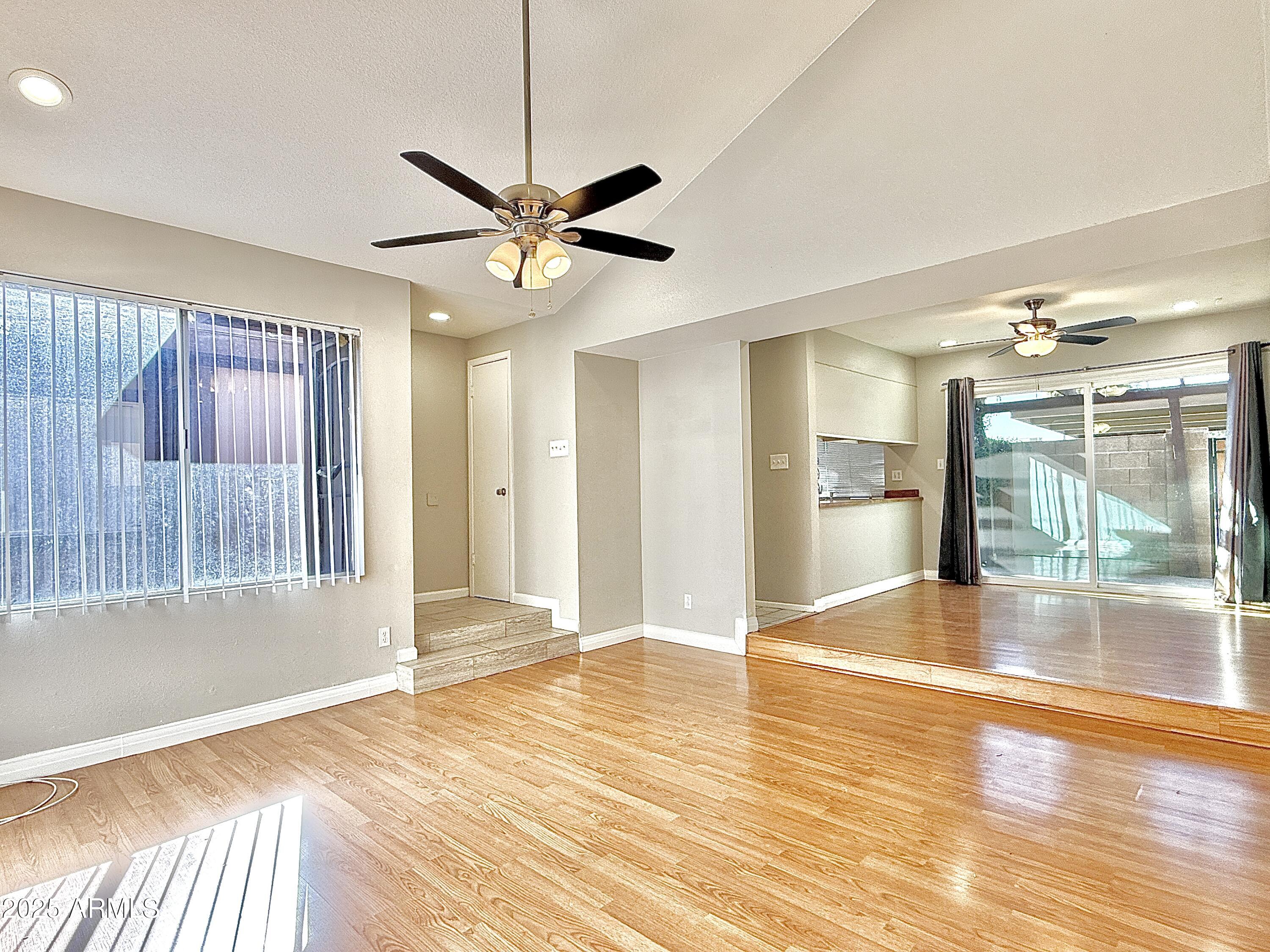 a view of an empty room with window and wooden floor