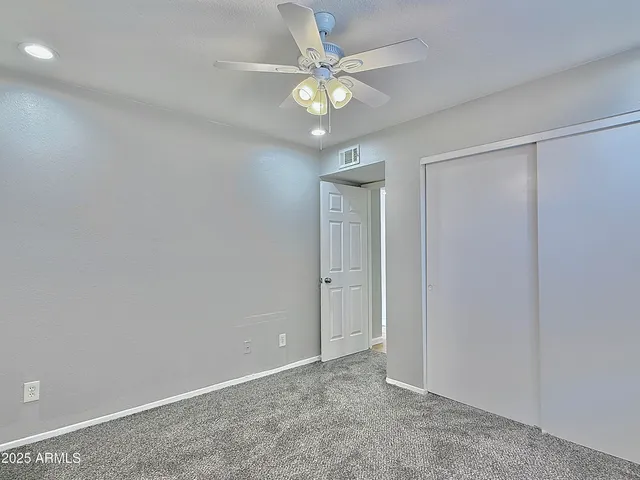 an empty room with closet and a chandelier fan
