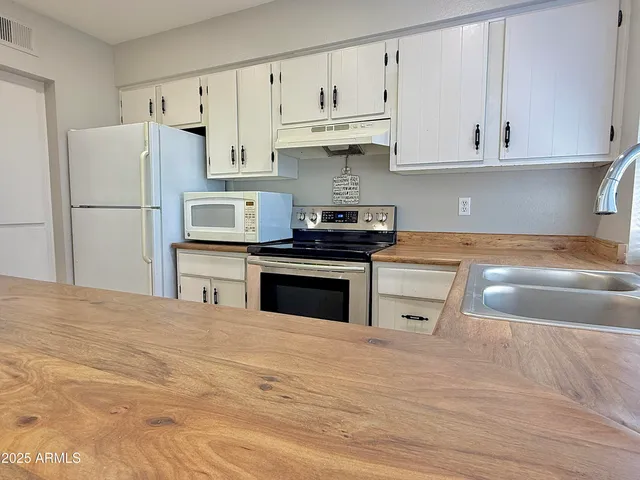 a kitchen with granite countertop white cabinets and refrigerator