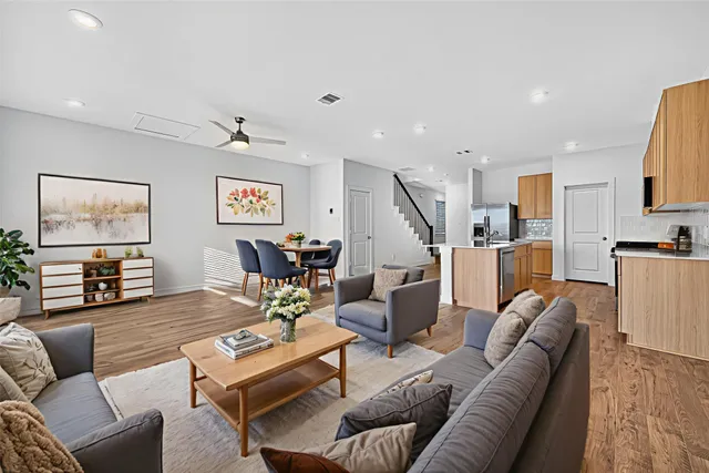 a living room with furniture kitchen view and a wooden floor
