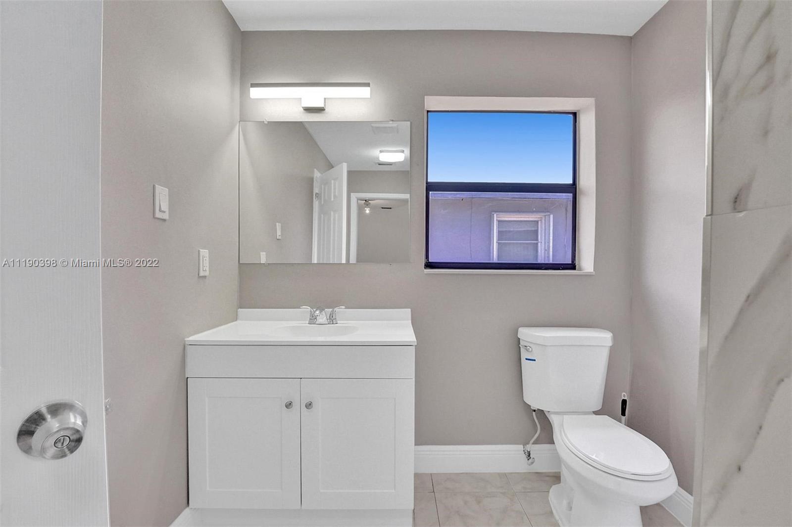 730 Northwest 18th Street Pompano Beach, FL 33060 - Photo 44 of 56 a bathroom with a toilet a sink a mirror and vanity