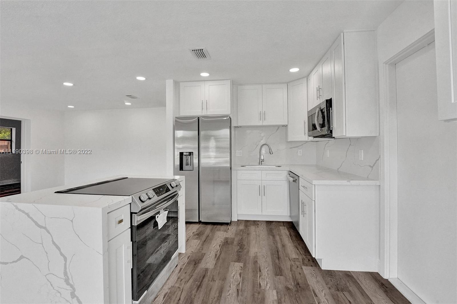 730 Northwest 18th Street Pompano Beach, FL 33060 - Photo 8 of 56 a kitchen with a refrigerator a sink and wooden floor