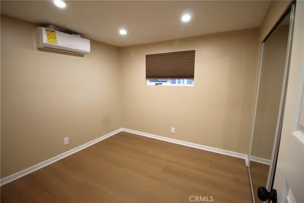 an empty room with wooden floor and mirror