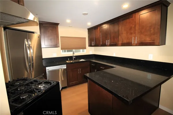 a kitchen with a sink and a stove top oven with wooden floor