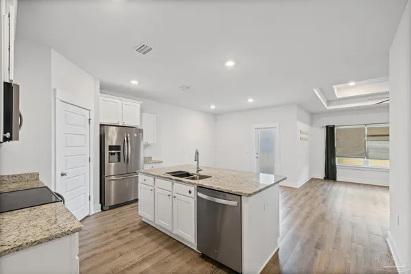 a kitchen with stainless steel appliances a refrigerator a stove top oven and wooden floors