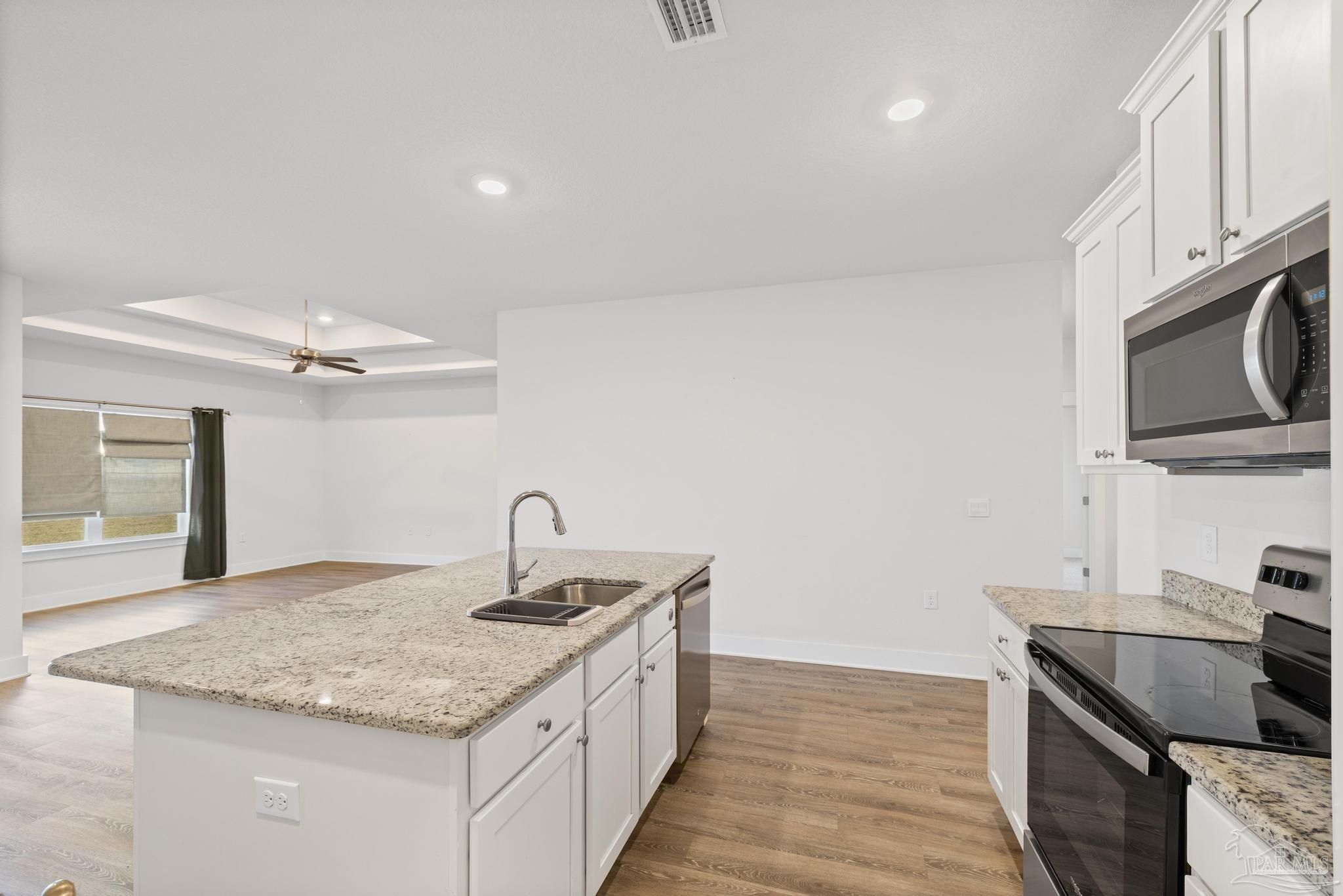 4074 Blaney Lane Pace, FL 32571 - Photo 41 of 59 a kitchen with granite countertop a sink and a stove top oven with wooden floor