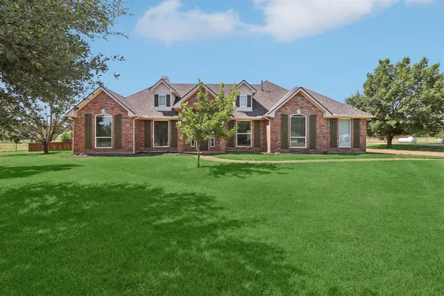 a front view of a house with a yard and trees
