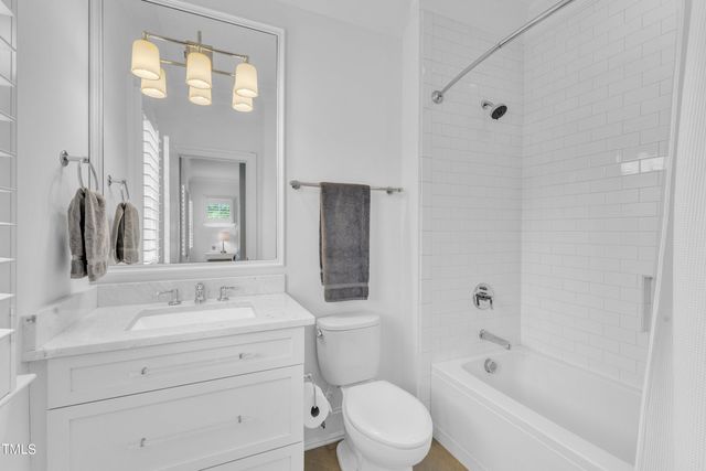 a bathroom with a bathtub shower sink vanity mirror and toilet