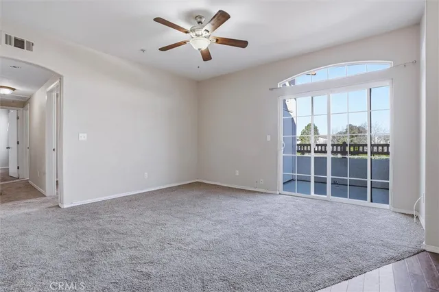 an empty room with windows and ceiling fan