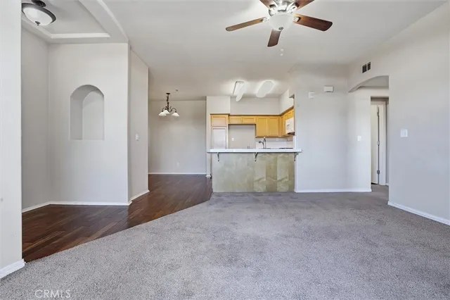 an empty room with chandelier fan and windows