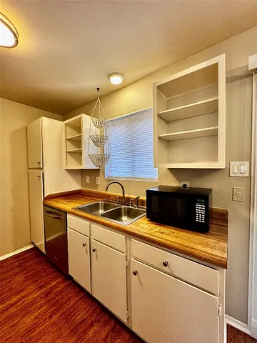 a kitchen with stainless steel appliances white cabinets and wooden floor