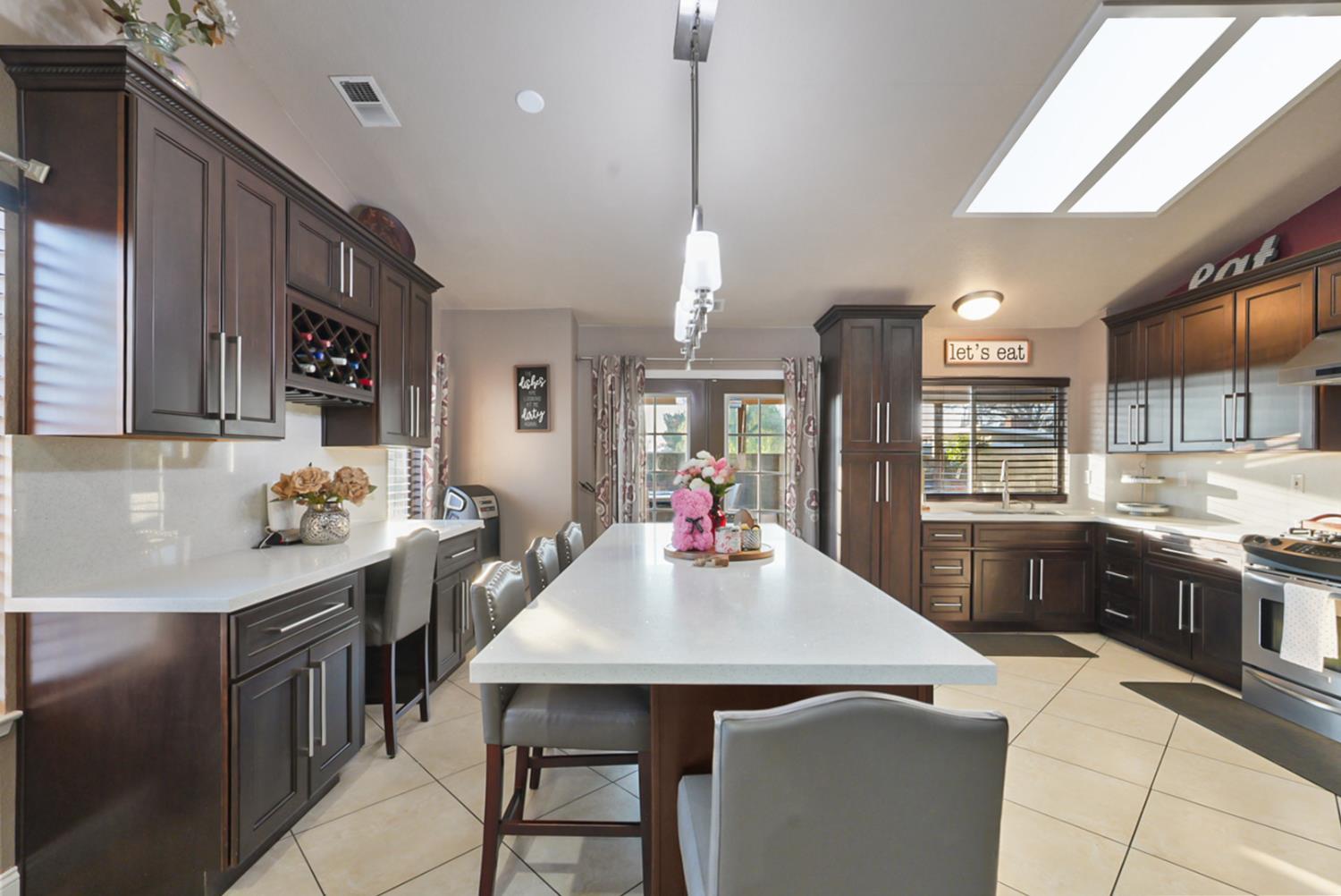 1421 Riverette Drive Modesto, CA 95351 - Photo 5 of 32 a kitchen with kitchen island a stove a sink a refrigerator and chairs