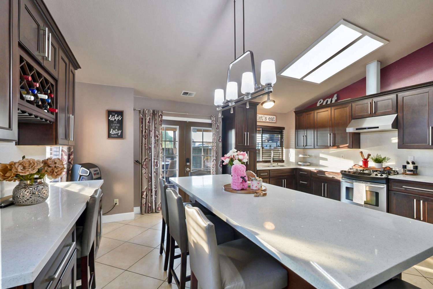 1421 Riverette Drive Modesto, CA 95351 - Photo 6 of 32 a kitchen with a stove a sink dishwasher a dining table and chairs with wooden floor