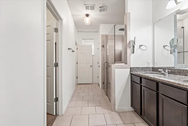 a bathroom with a granite countertop shower a mirror and a sink