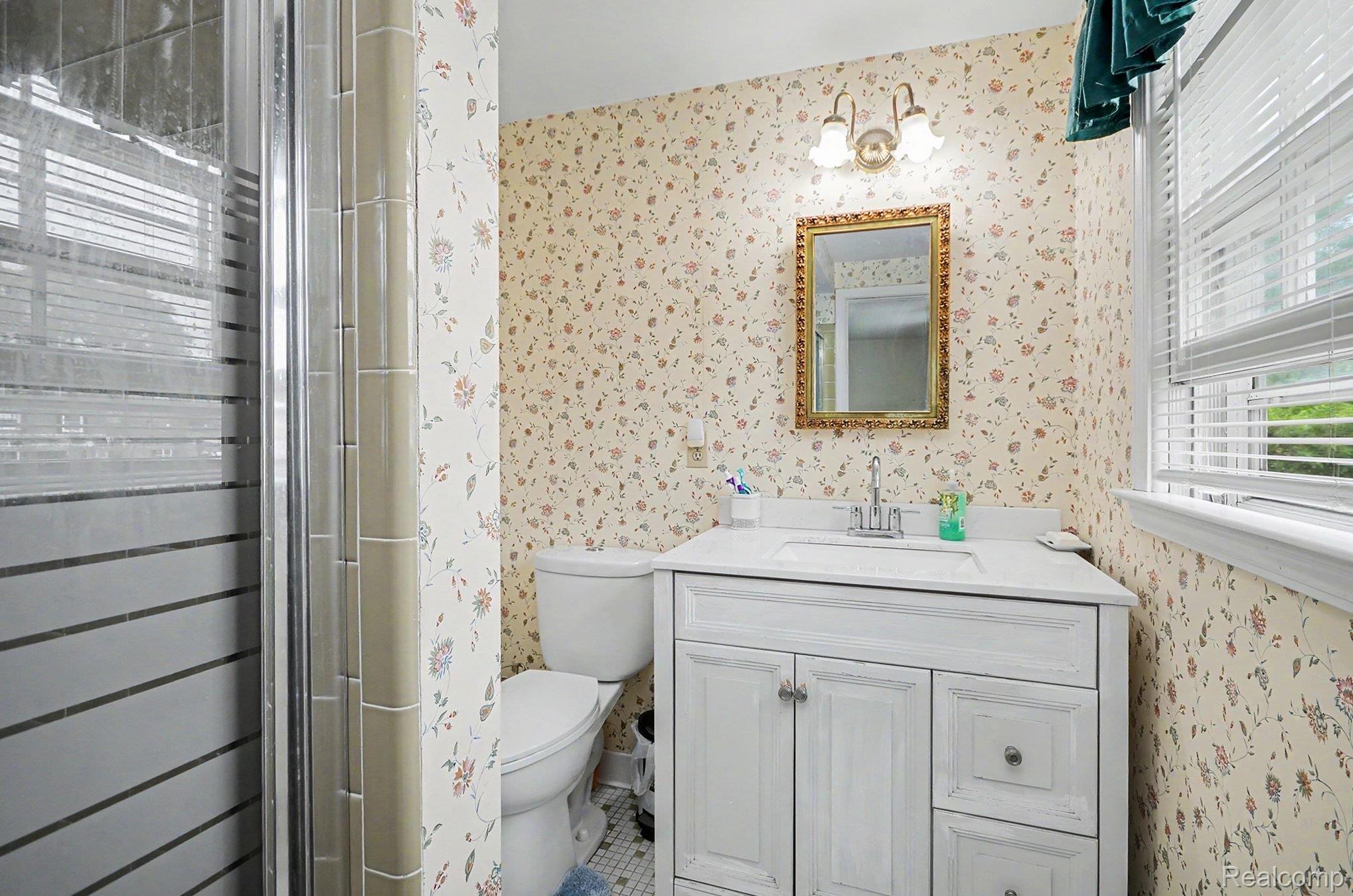 6653 Flintlock Ridge Utica, MI 48317 - Photo 20 of 31 Bathroom featuring a white vanity with integrated sink, gold-framed mirror, and floral wallpaper