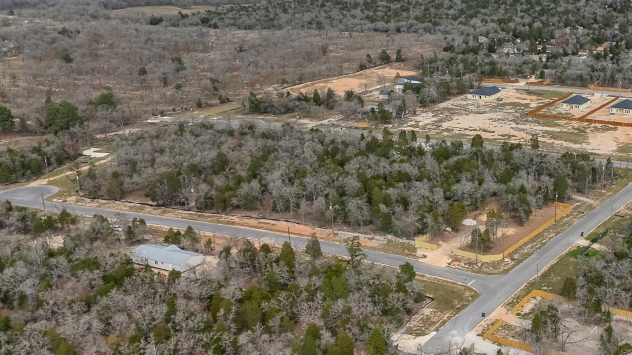 113 Las Alturas Drive Elgin, TX 78621 - Photo 5 of 5 An aerial perspective reveals a developing neighborhood nestled amidst a tree-filled landscape with new constructions.