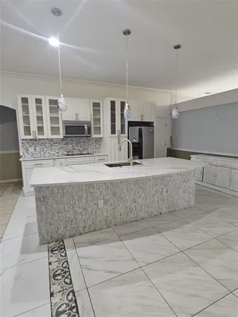 a large kitchen with kitchen island granite countertop a sink a counter top space and cabinets