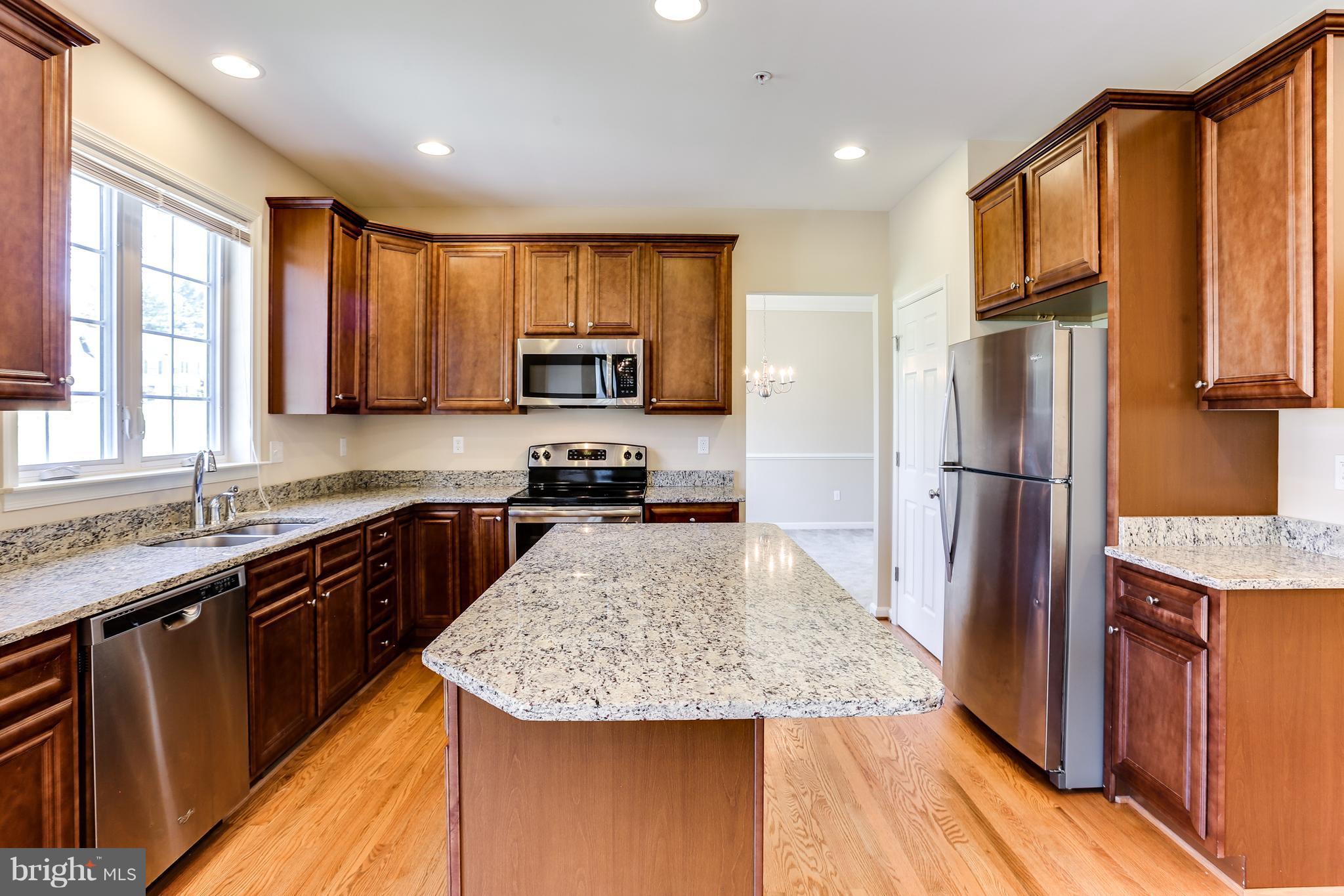 6020 Cypress Springs Road Elkridge, MD 21075 - Photo 7 of 29 a kitchen with kitchen island granite countertop wooden cabinets a refrigerator and a sink