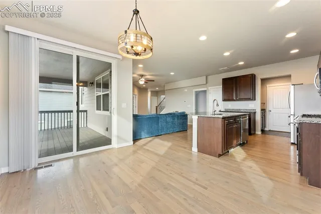 an empty room with wooden floor chandelier and windows