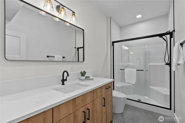 a bathroom with a shower sink vanity mirror and toilet