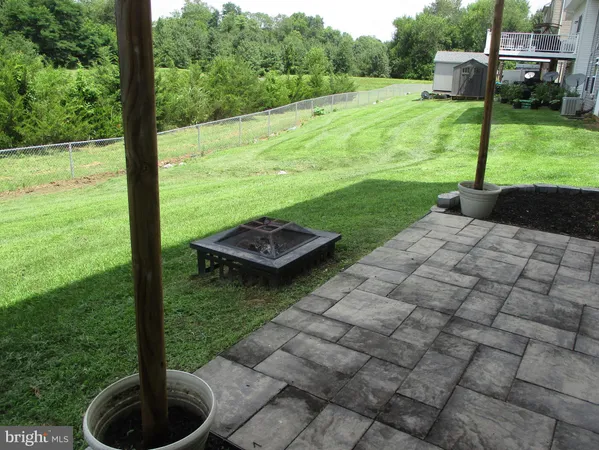 a view of a patio with lawn chairs plants and large trees