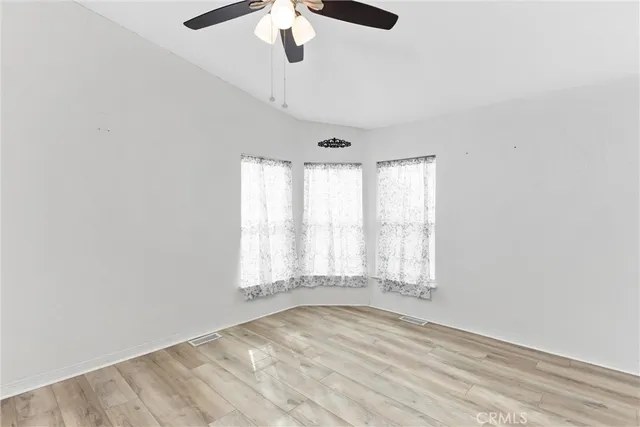 an empty room with a window and a ceiling fan