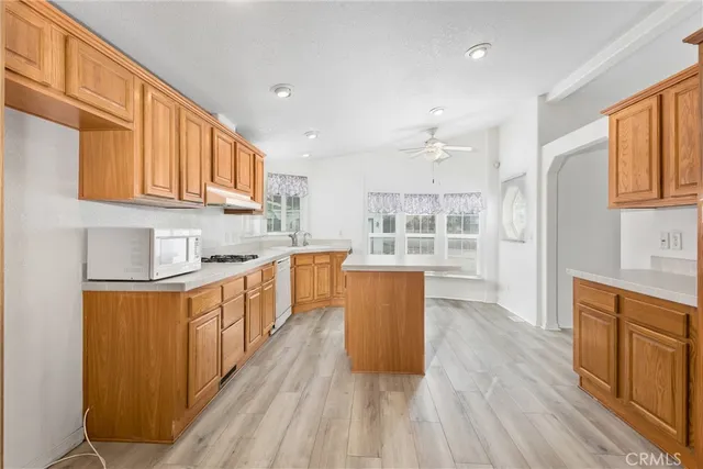 a kitchen with stainless steel appliances granite countertop a stove top oven a sink dishwasher and a refrigerator with wooden floor