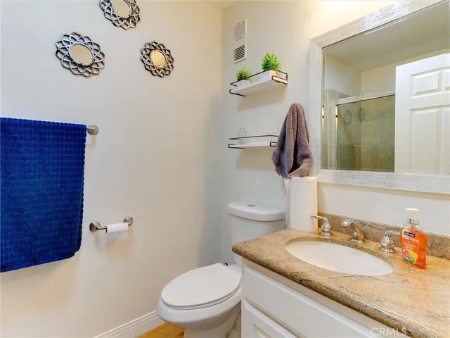 a bathroom with a granite countertop toilet sink and mirror