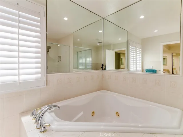 a bathroom with a tub a mirror and a shower