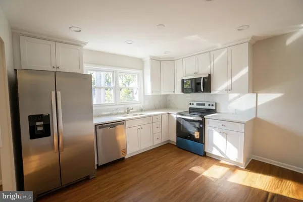 a kitchen with granite countertop stainless steel appliances a sink a window and cabinets