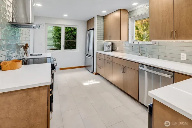 a large white kitchen with a sink a window and stainless steel appliances
