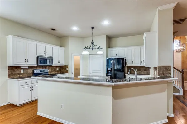 a kitchen with kitchen island granite countertop a sink stainless steel appliances and cabinets