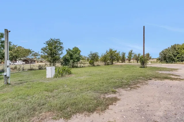 a view of a grassy field with trees in the background