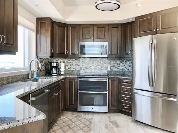a kitchen with stainless steel appliances granite countertop a refrigerator sink and stove