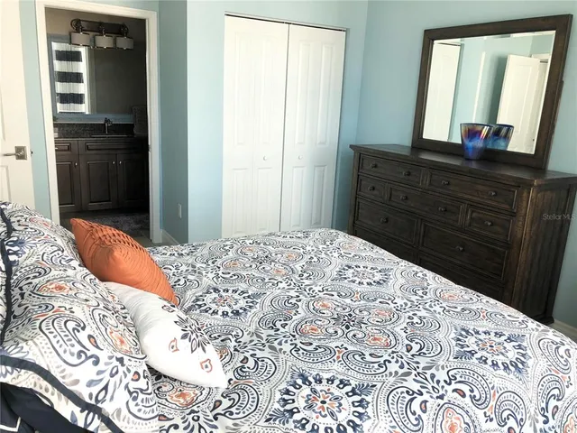 a bedroom with a bed and a mirror on dresser