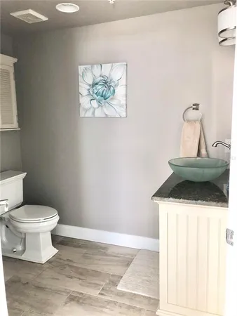 a bathroom with a toilet a sink and wooden floor