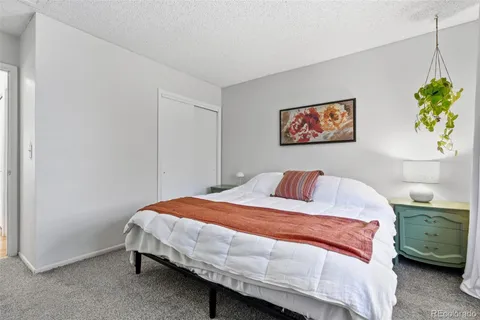 a bedroom with a bed a wall painting and a potted plant